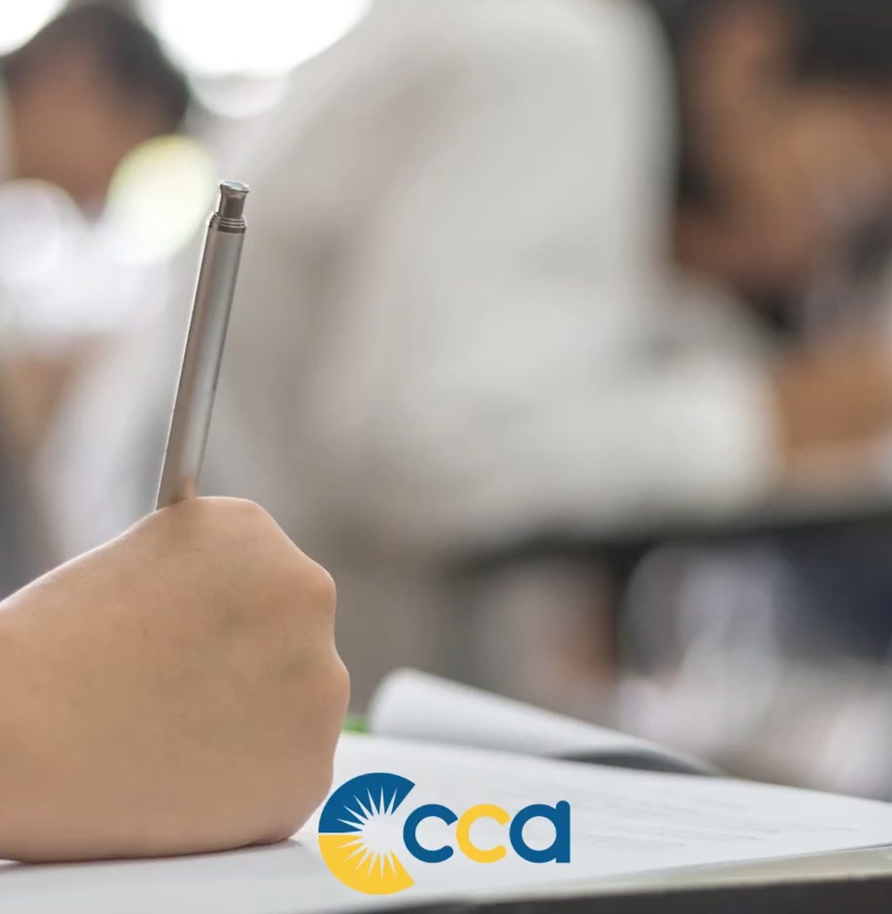 Image of a student writing on paper with the CCA logo.