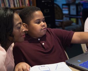 a teacher helping a student on the laptop