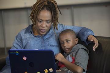 A parent teaching her child something on the laptop.