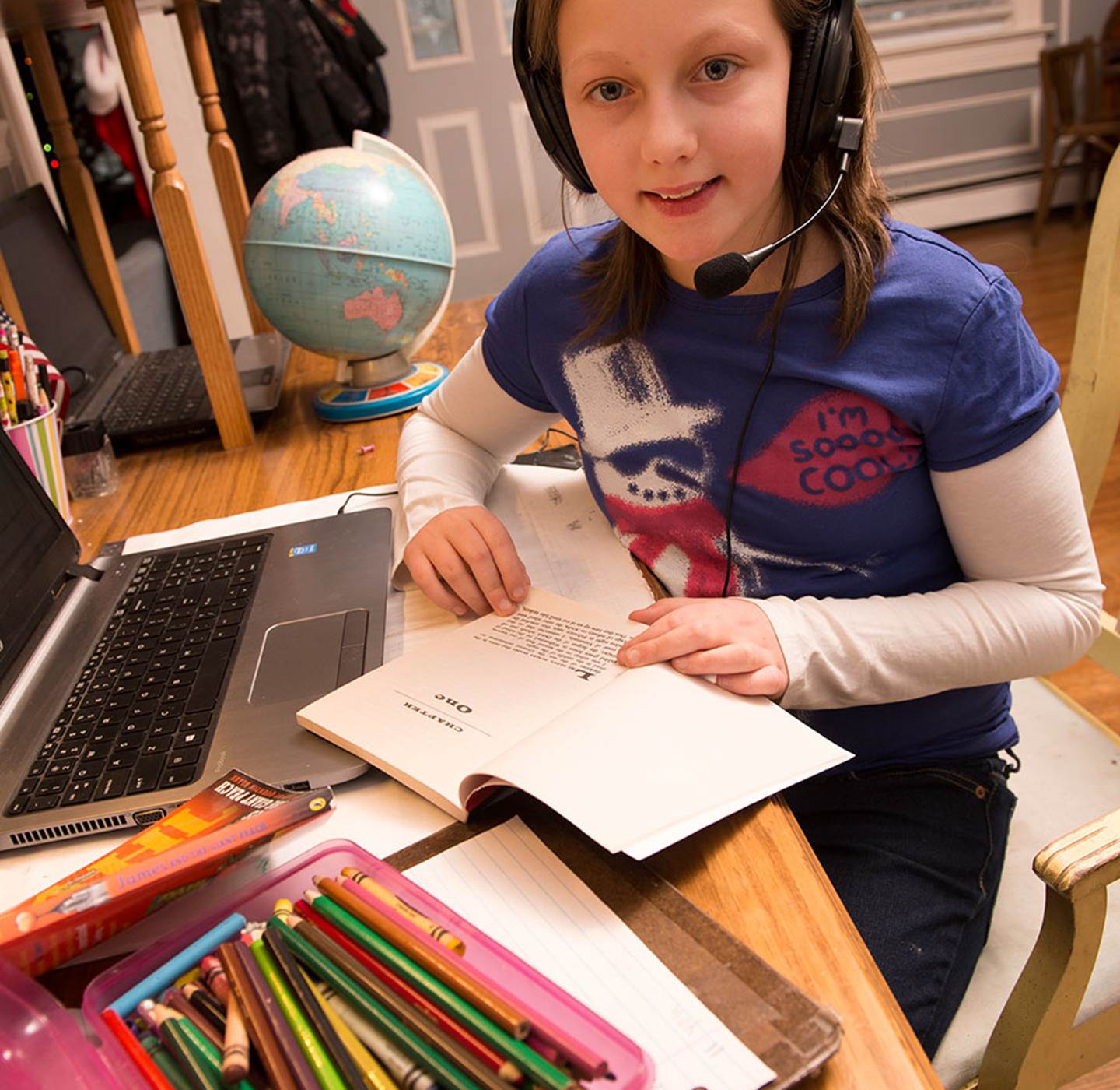 A student reading a book with a headset on.