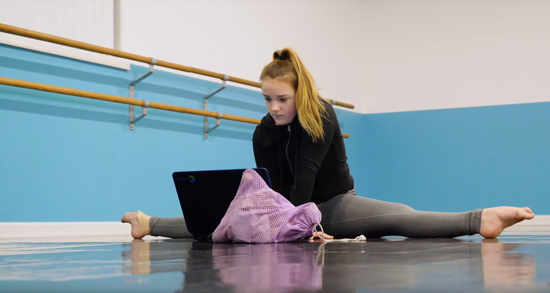 Jordyn Perez on the computer while doing a split.