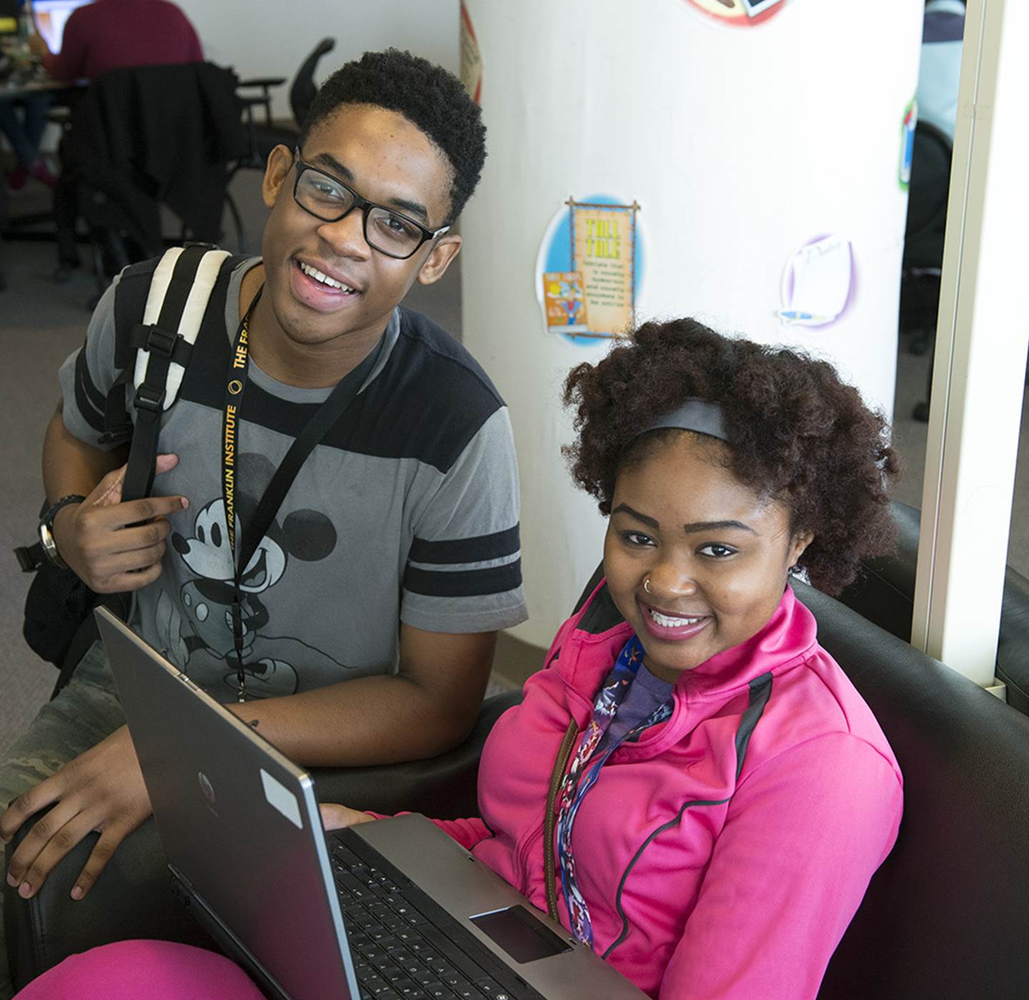 Two students posing behind a laptop.