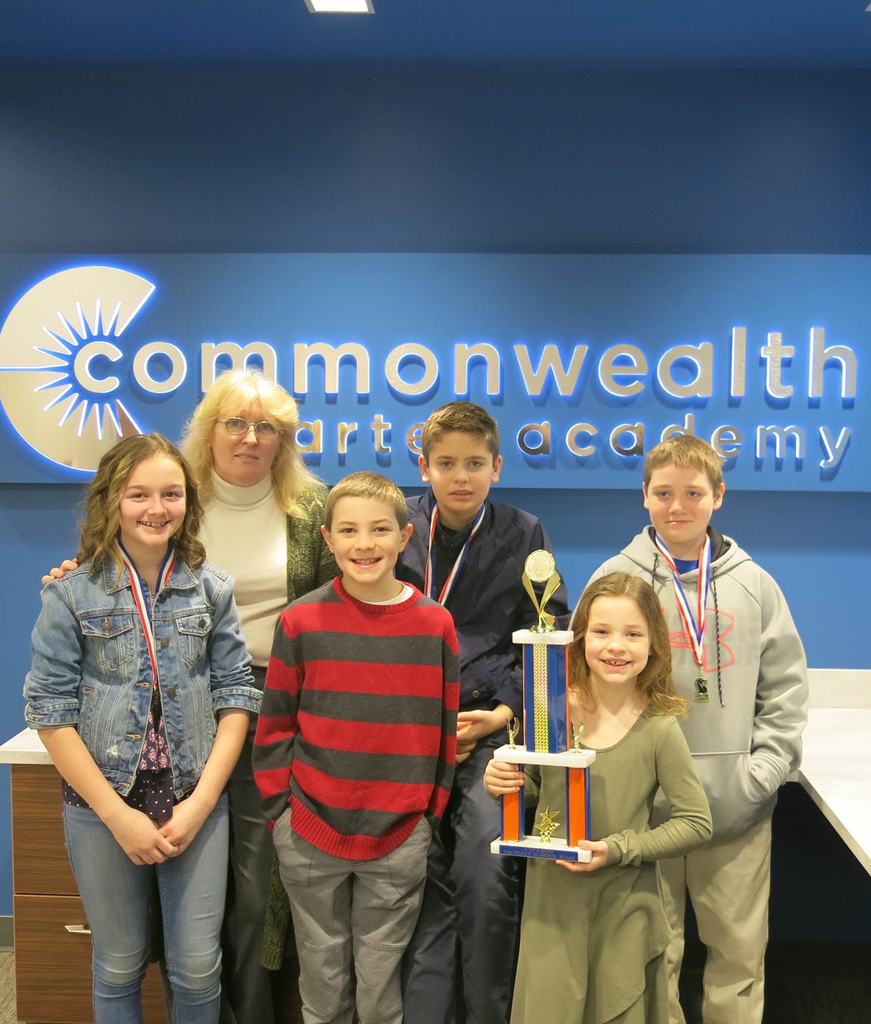 The chess team comprised of five children and the coach holding their trophy.