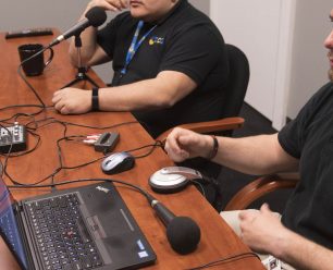 Two people in front of podcasting equipment.