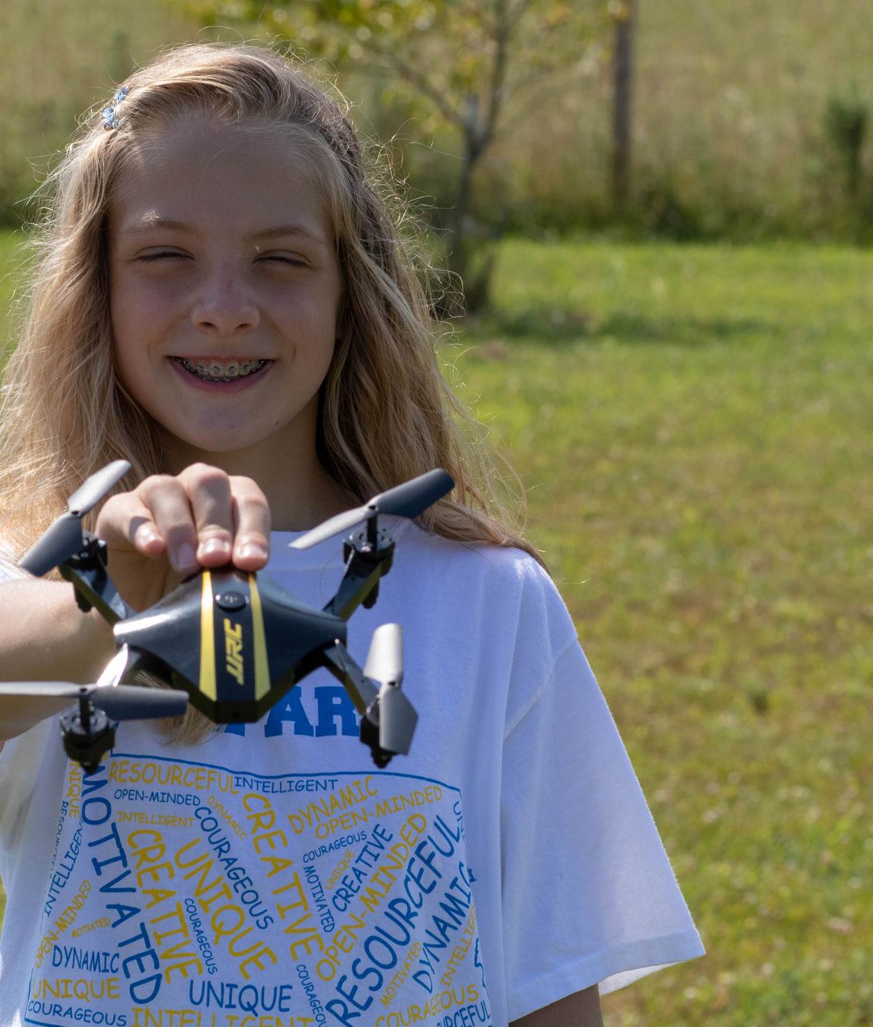A girl holding her drone and smiling.