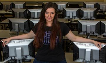 Courtney Thurston posing in front of computer monitors.