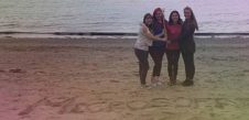 Courtney Thurston posing on a beach with three other women.