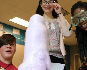 Students watching the chemical reaction of the liquids and powder in the plastic bottle.