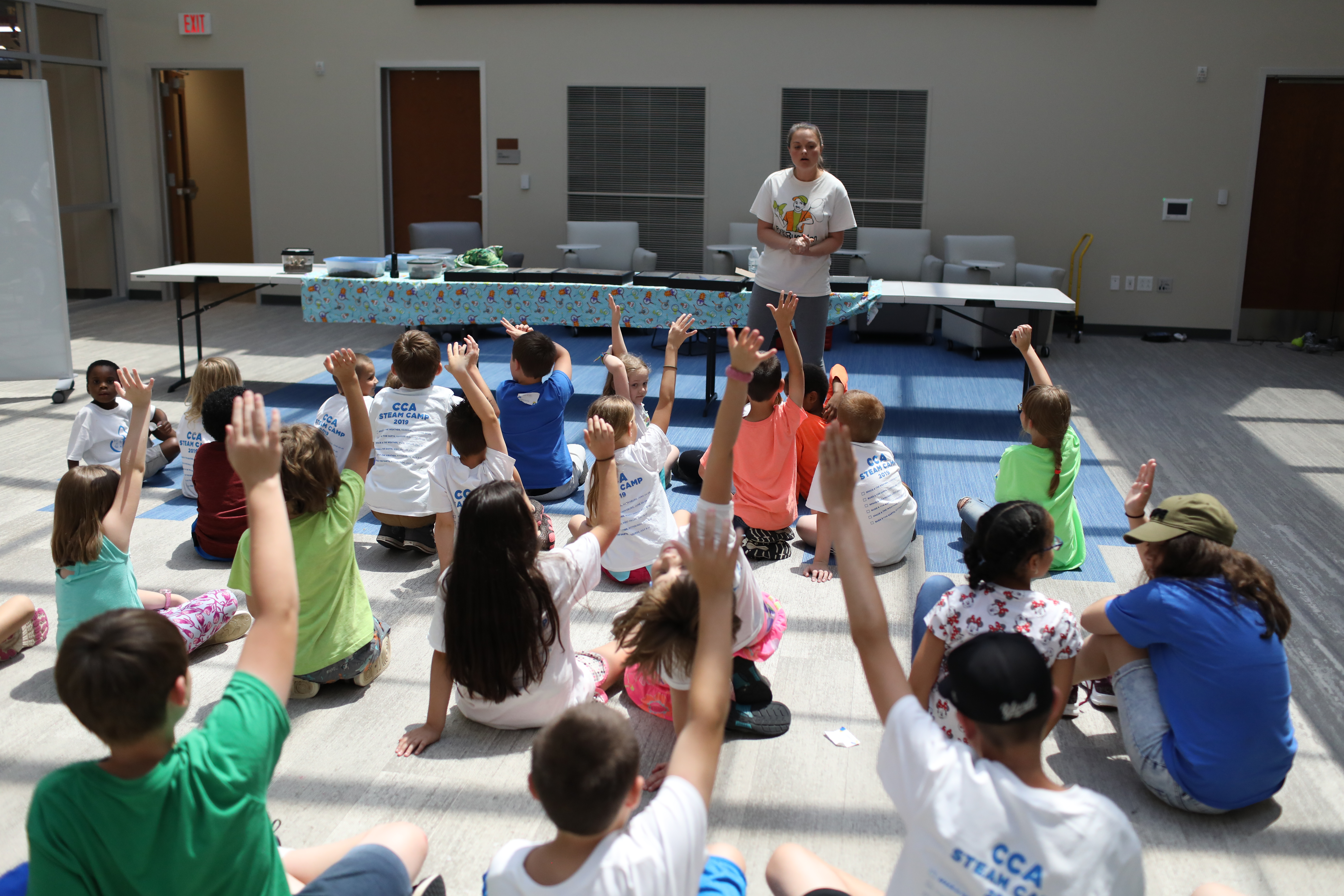 CCA students raising their hands at a STEAM camp event