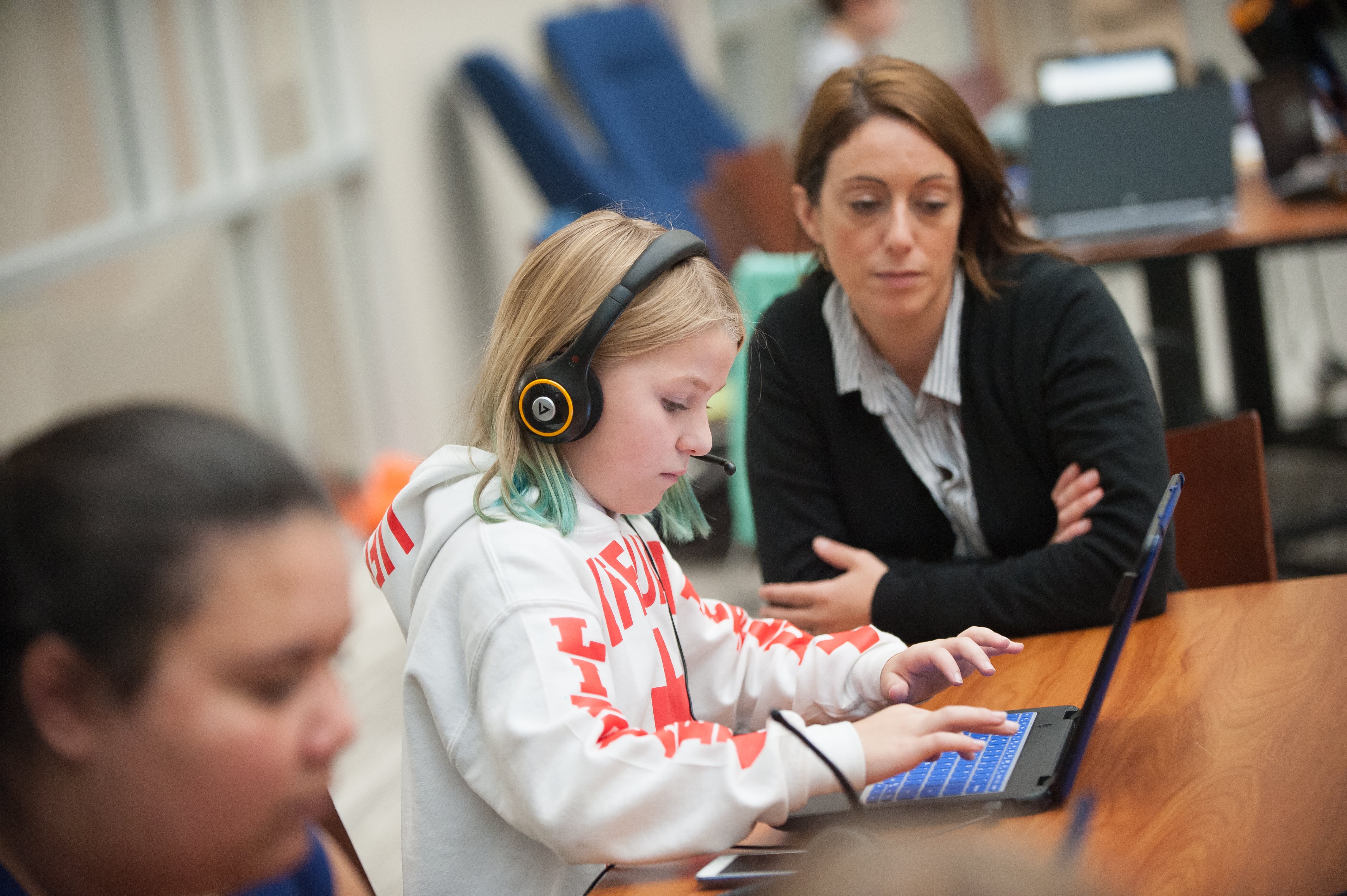 Student typing on a keyboard with her learning coach