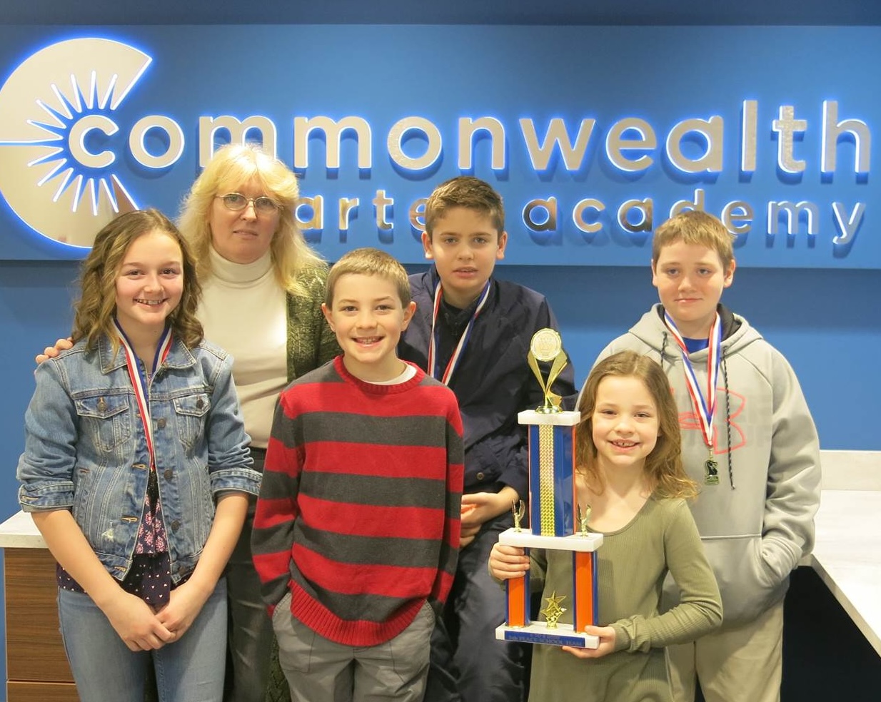 The chess team comprised of five children and the coach holding their trophy.