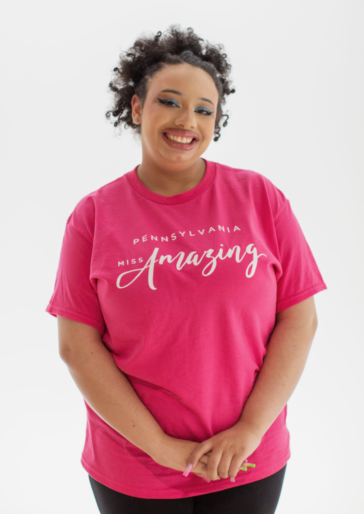 Jaylene smiles big in her Pennsylvania Miss Amazing hot pink t-shirt.